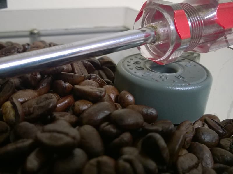 A burr coffee grinder next to whole coffee beans